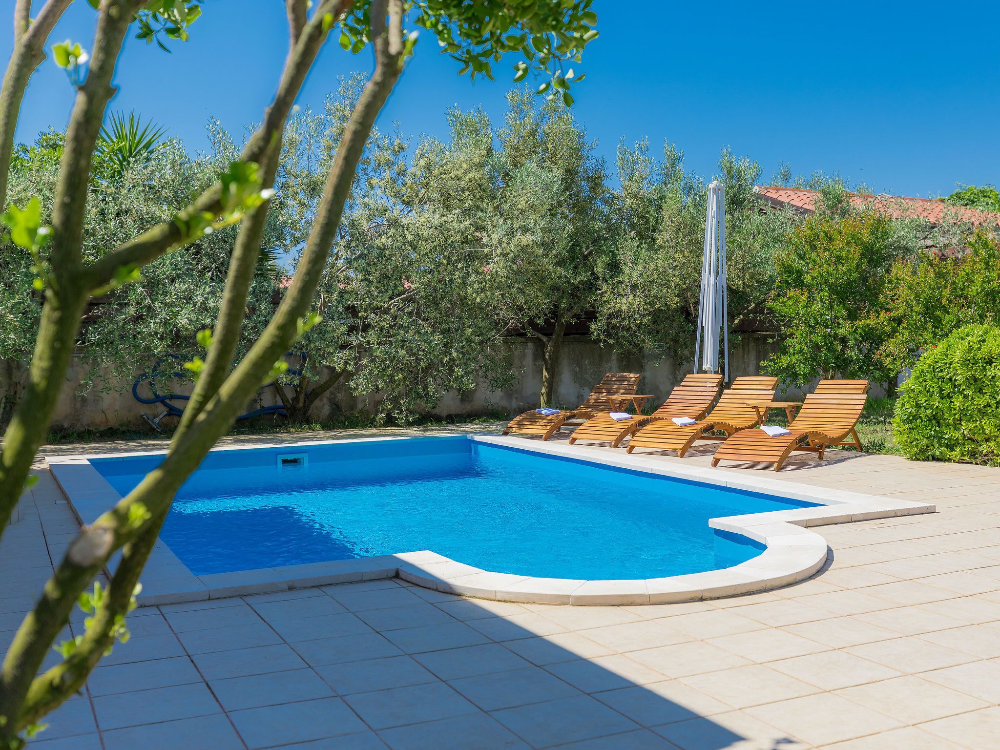 A swimming pool with wooden lounge chairs and a pergola.