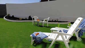 A poolside area with white lounge chairs, a small table, and a drink tray.
