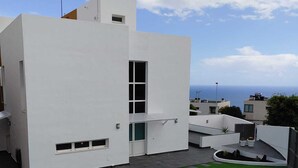 A modern white building with a flat roof, a small window, and a satellite dish.