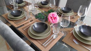 A dining table set with plates, bowls, glasses, and cutlery, surrounded by chairs.
