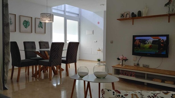 A modern living room with a dining area, a television, and a large window.