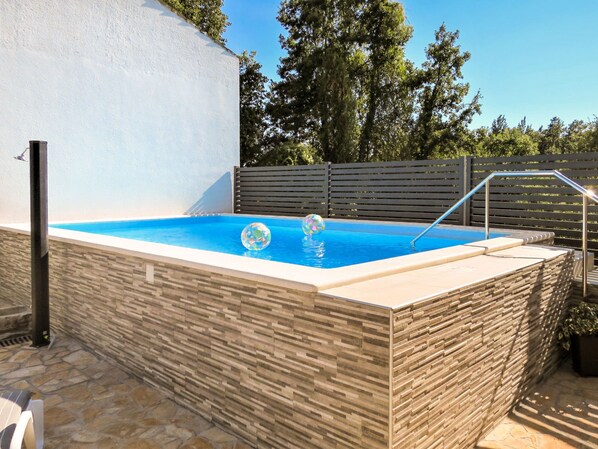 A rectangular swimming pool with a stone wall surrounding it, a wooden fence, and a metal ladder. - Milka 2 by Interhome (Rovinj)