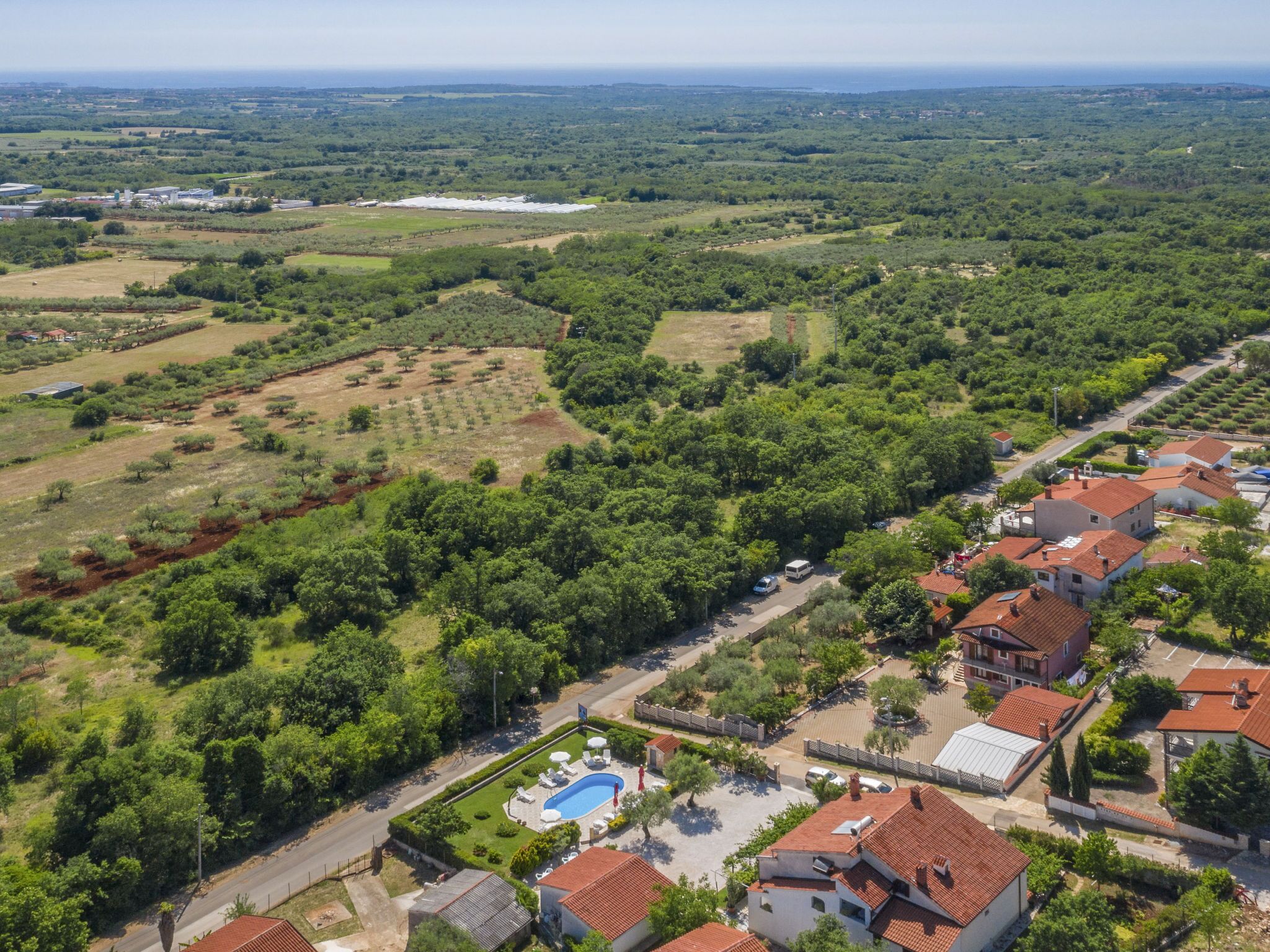 Vue aérienne d’un quartier résidentiel avec des maisons, une piscine et de la végétation environnante.