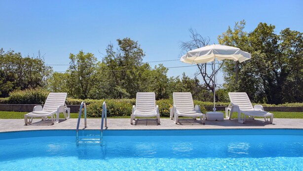 A swimming pool with white lounge chairs and a white umbrella. - Apartment Jukić by Interhome (Poreč/Kaštelir)
