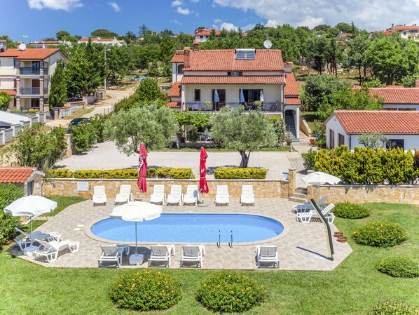 A pool area with lounge chairs and umbrellas, surrounded by well-maintained lawns and trees. - Apartment Jukić by Interhome (Poreč/Kaštelir)