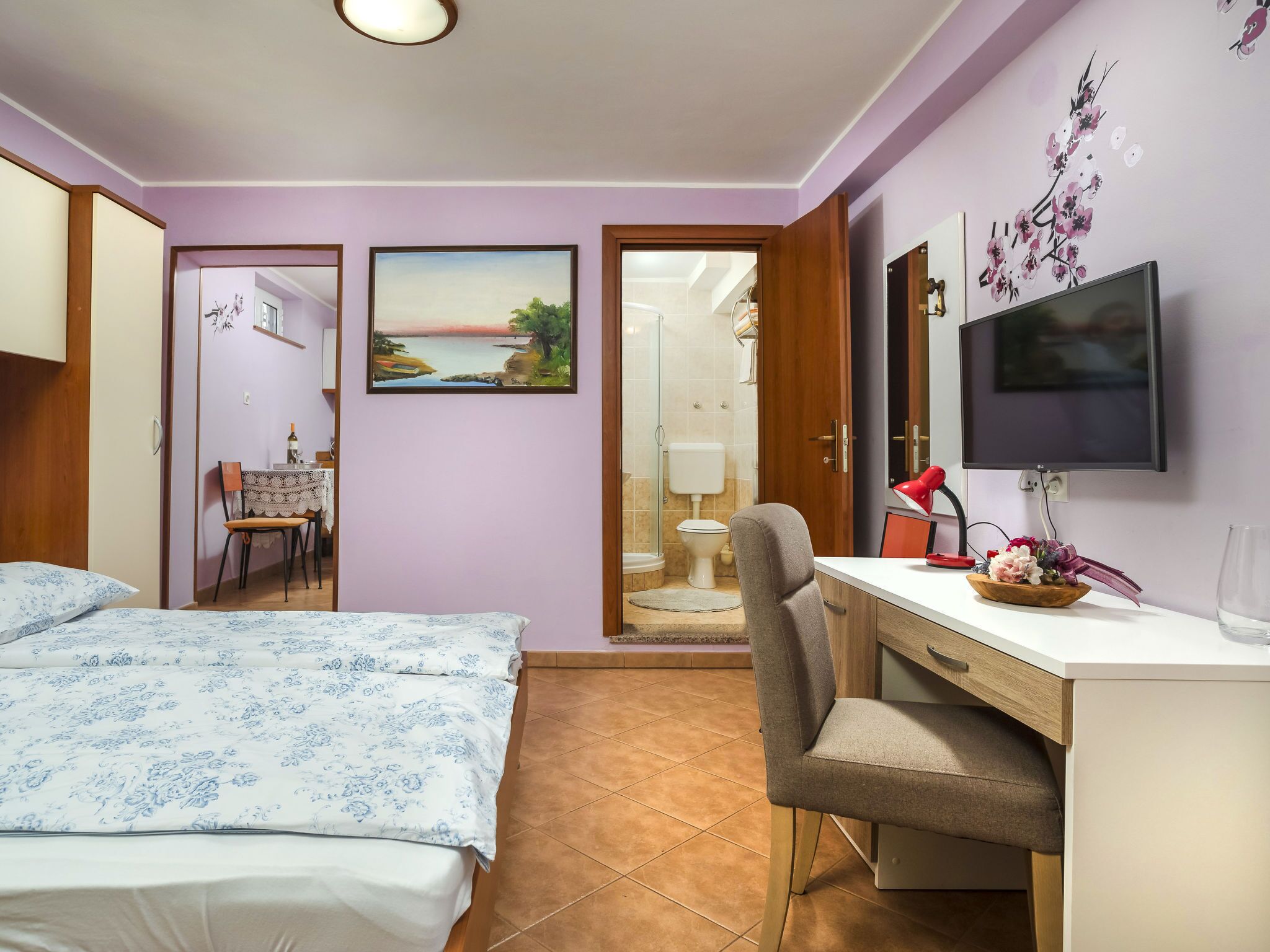 Une chambre à coucher avec un lit, un bureau, une chaise, un téléviseur et un tableau accroché au mur.