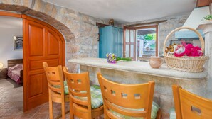 Una cocina rústica con paredes de piedra, sillas de madera y una zona de bar con un cesto de flores.
