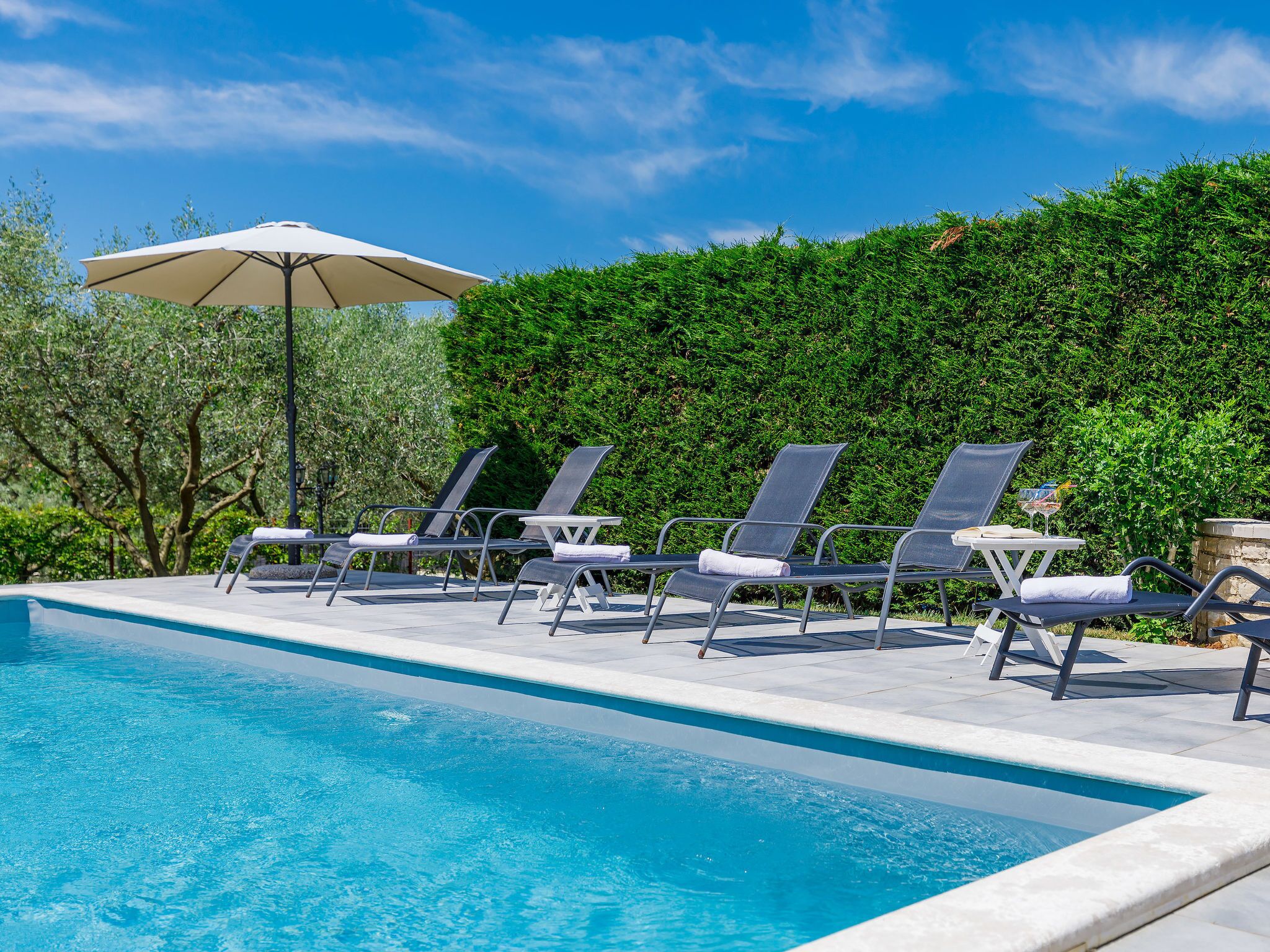 Una piscina con sillas de descanso y una sombrilla.