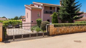 A pink building with a stone wall and a metal gate. - Apartment Koštro by Interhome (Poreč)