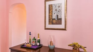 A wooden dresser with a tray holding bottles, glasses, and a small plant. A framed artwork hangs above the dresser.
