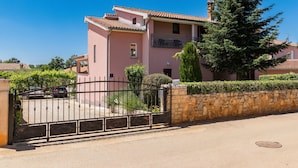 A pink building with a stone wall and a metal gate.