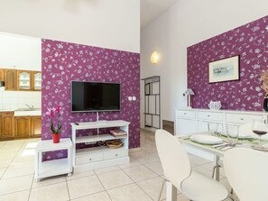 Cozy living space with a kitchen and dining area, featuring a flat-screen TV and a beautifully set table for two.
