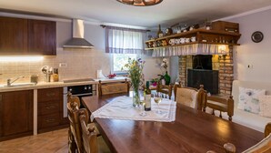 A cozy kitchen with wooden cabinets, a dining table with chairs, and a fireplace. - Vacation home Mariva by Interhome (Pićan)