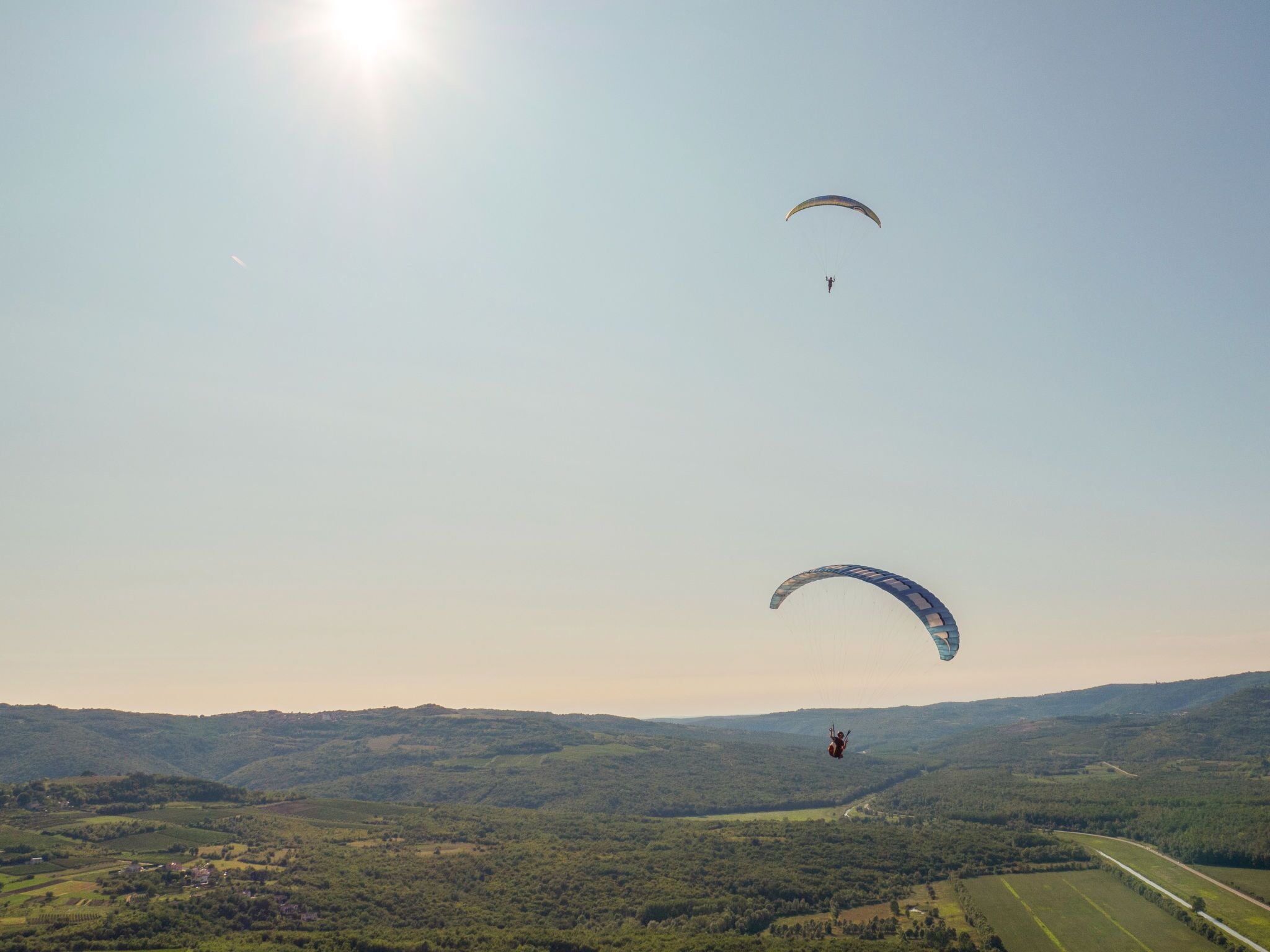 A landscape with two paragliders and a road.
