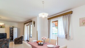 Un coin repas avec une table dressée pour quatre personnes, un téléviseur en arrière-plan et un meuble avec des portes en verre.