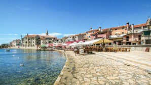 A waterfront promenade with stone paving, outdoor seating, and a clear view of the sea. - Antonella & Napoletano by Interhome (Umag)