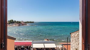 A coastal view from a building with a stone facade, overlooking a beach with a restaurant named "Burgers & More". - Antonella & Napoletano by Interhome (Umag)