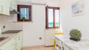 Eine Küche mit Meerblick, eine Essecke mit Tisch und Stühlen sowie ein Blumentopf.
