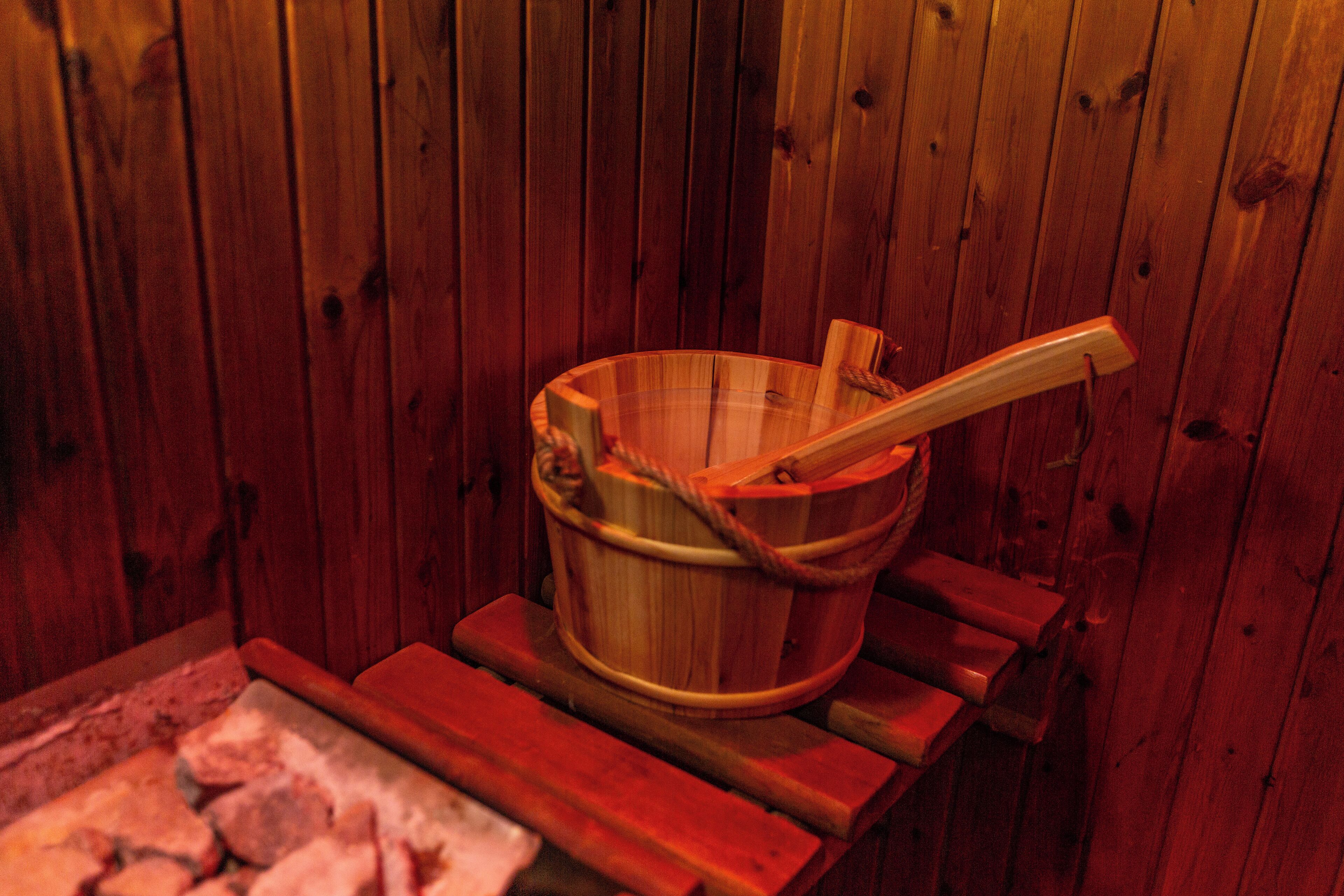 Un sauna en bois, avec un seau en bois et une louche en bois.