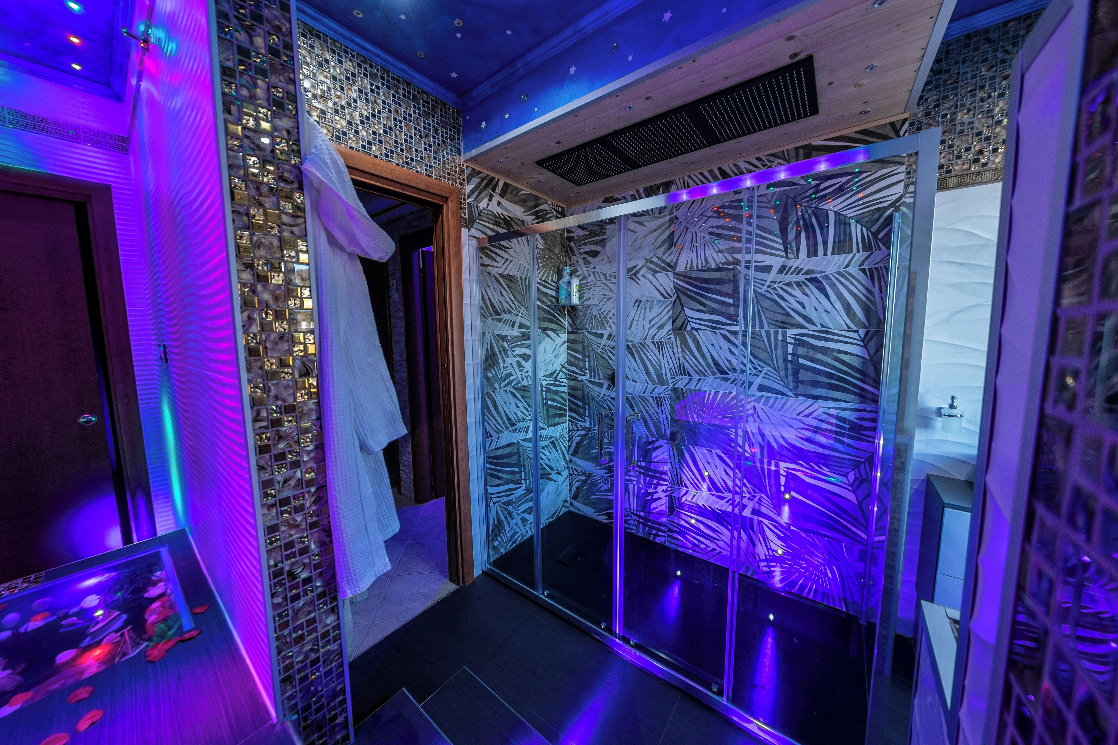 Ein modernes Badezimmer mit Glasabtrennung, Holzboden und gefliesten Wänden.