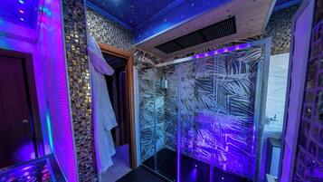 Ein modernes Badezimmer mit Glasabtrennung, Holzboden und gefliesten Wänden.