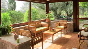 Une terrasse couverte, aménagée avec des meubles en bois, une table en pierre et des plantes en pot.