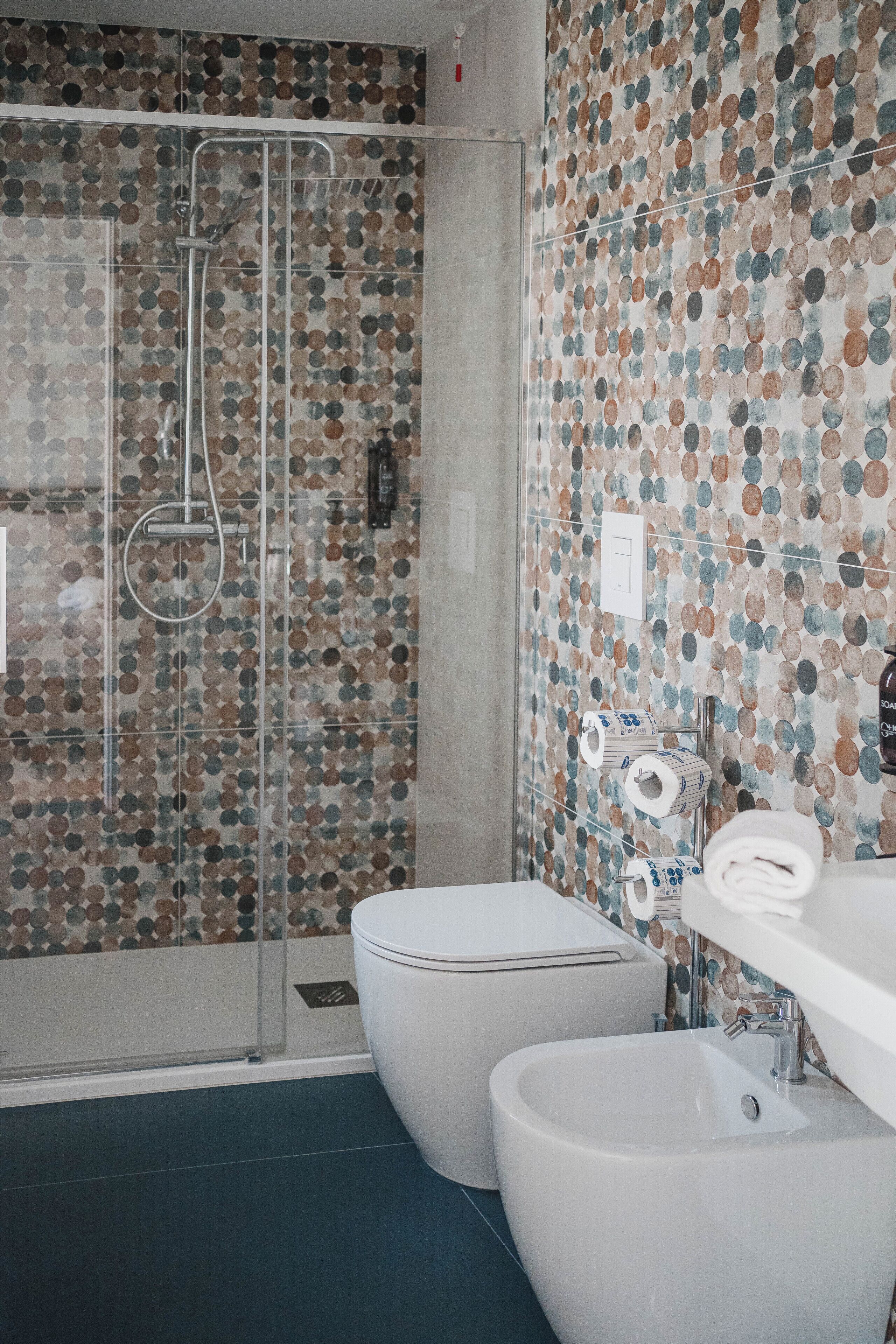 A bathroom with a shower, toilet, and bidet.