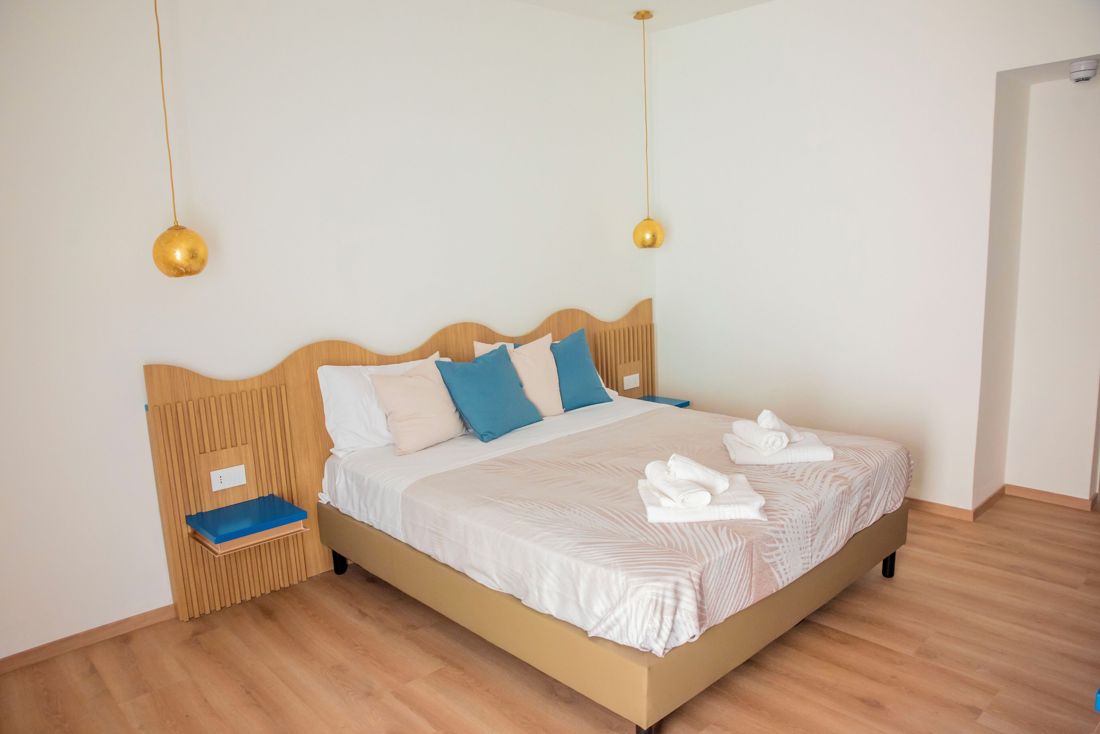 A neatly made bed with a wooden headboard, two bedside tables, and a blue tray.