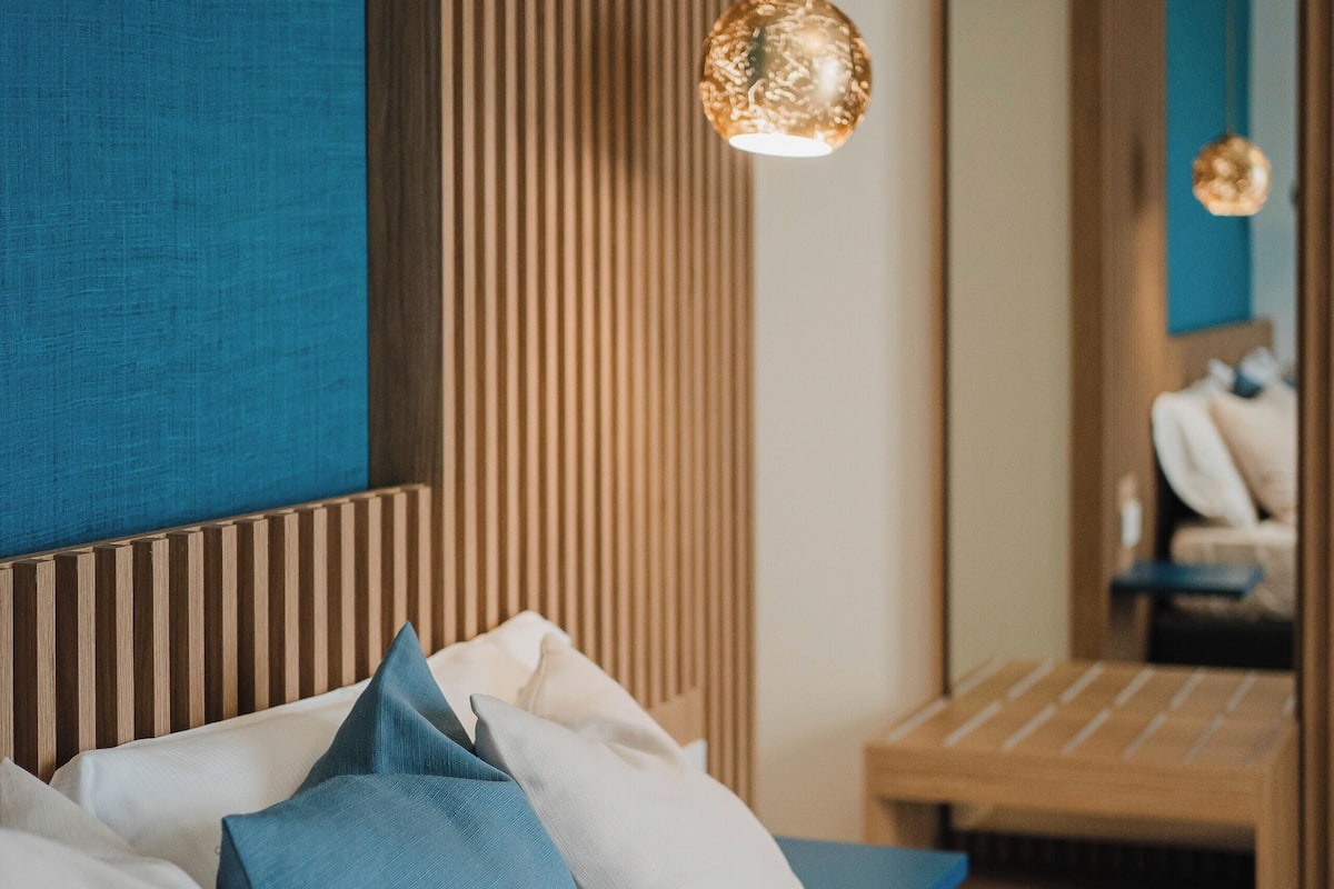 Ein modernes Schlafzimmer mit Bett, Kissen, Nachttisch und einer Pendelleuchte.
