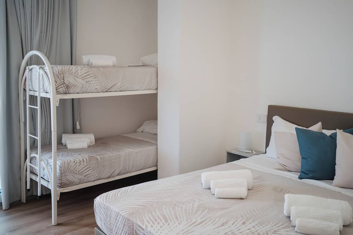 Ein Hotelzimmer mit Etagenbett, einem Einzelbett und einem Nachttisch mit Lampe.