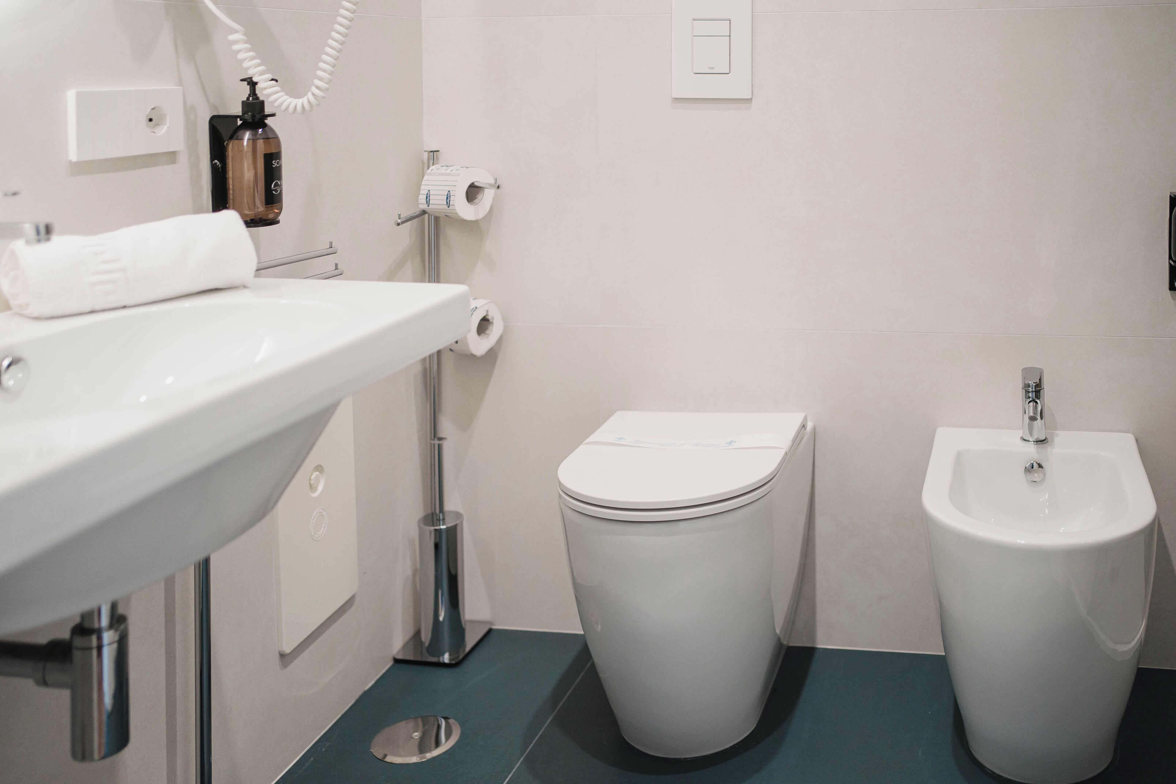 Un baño moderno con lavamanos, inodoro y bidé blancos.