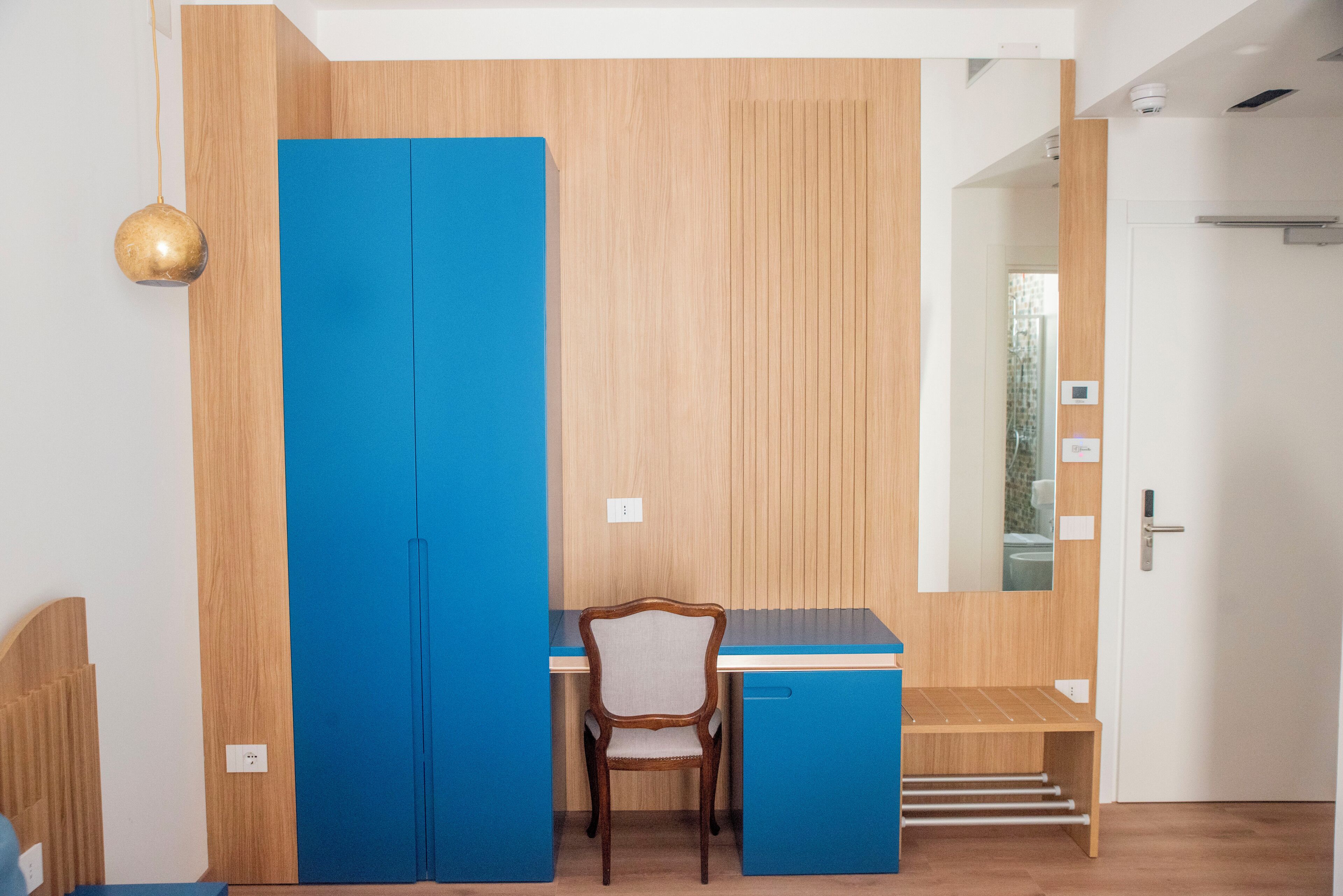 A modern room with a wooden desk, a chair, and a blue wardrobe.