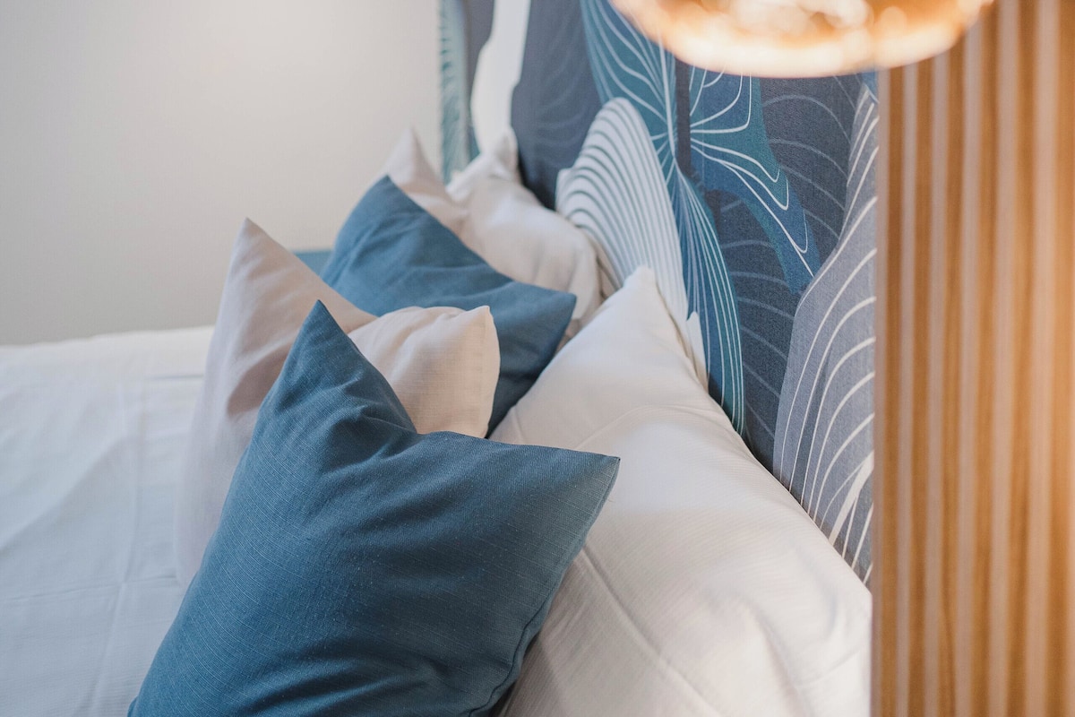 Ein Schlafzimmer mit einem Bett, Kissen und einer Hängelampe.
