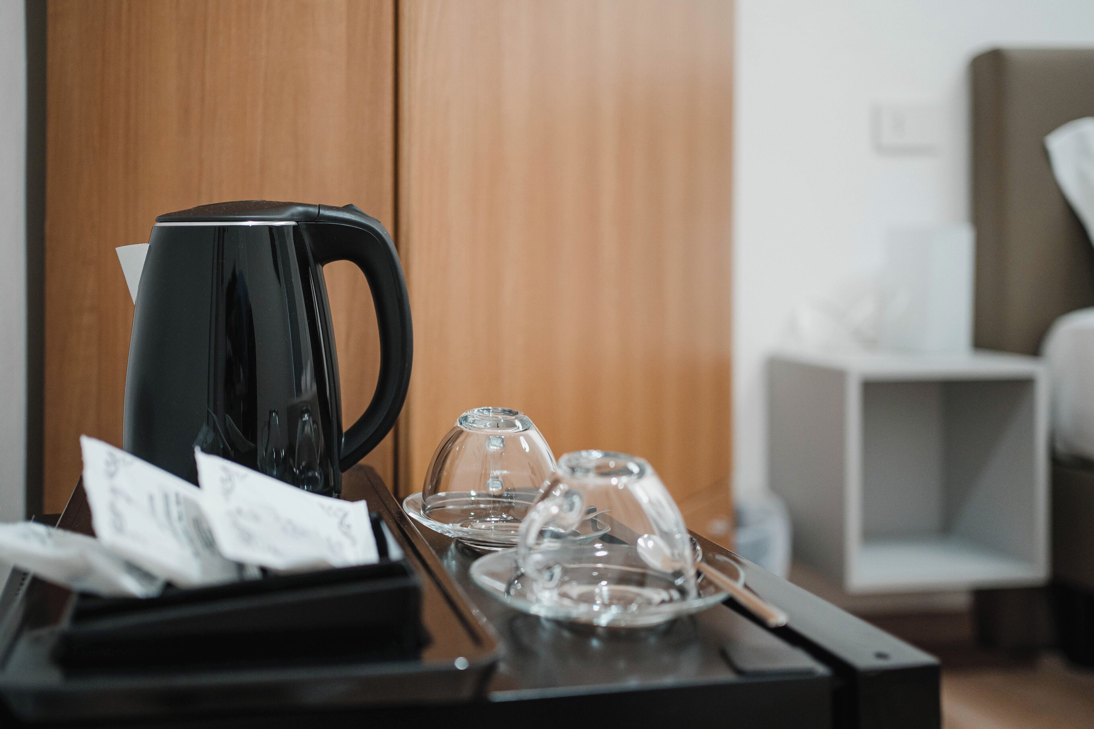 A coffee station with a black coffee maker, clear glass cups, and a tray with receipts.