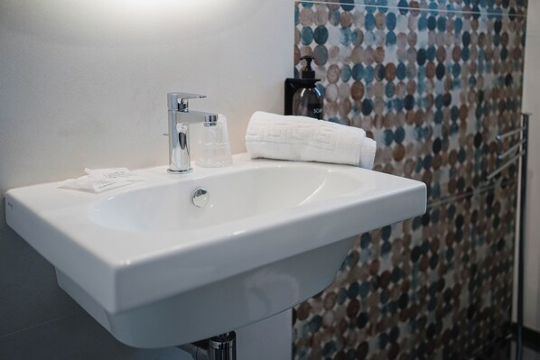 A white bathroom sink with a faucet, a glass, and a towel on the counter. - Hotel Ficocella (Centola)