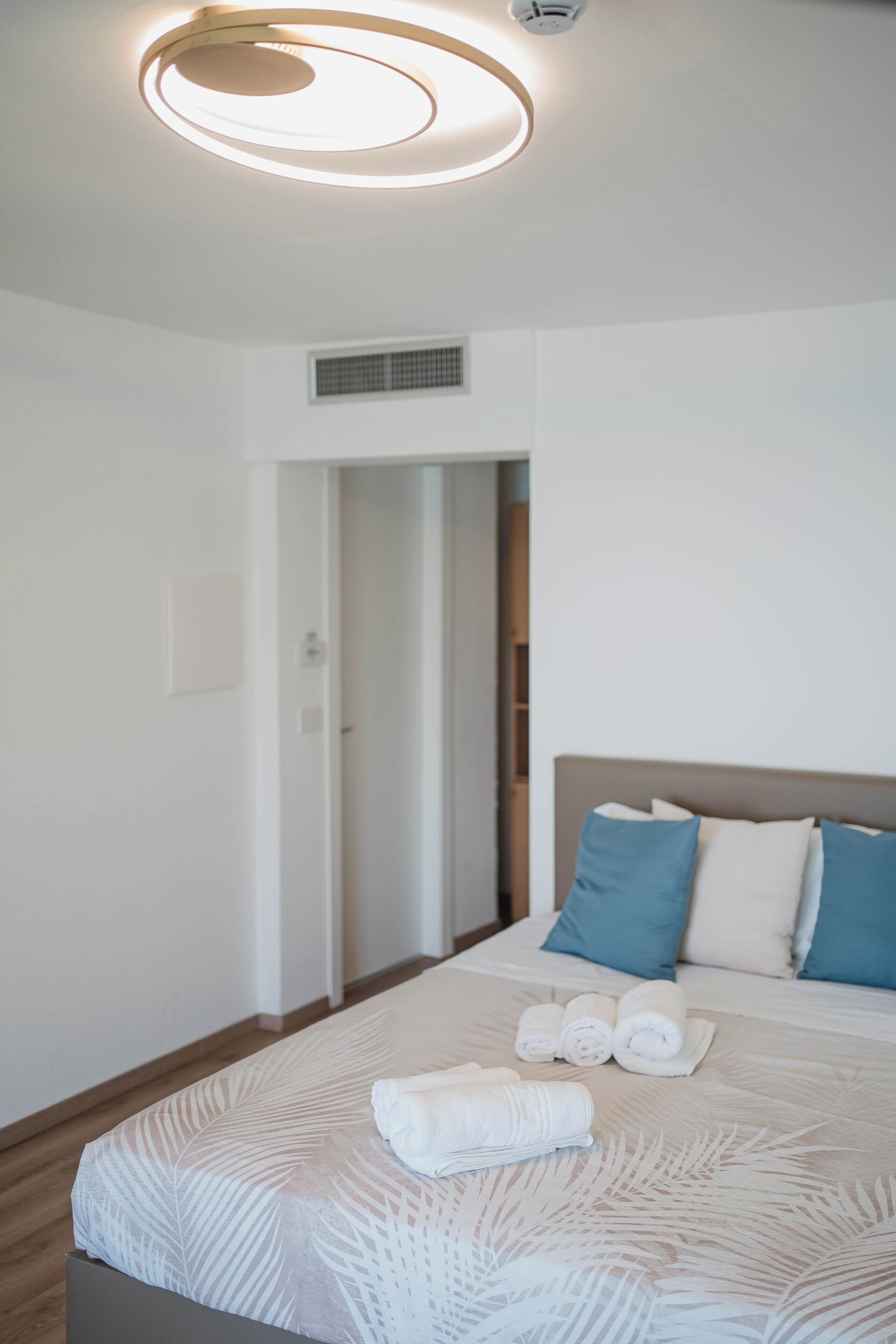 A hotel room with a bed, a ceiling light, and a door.