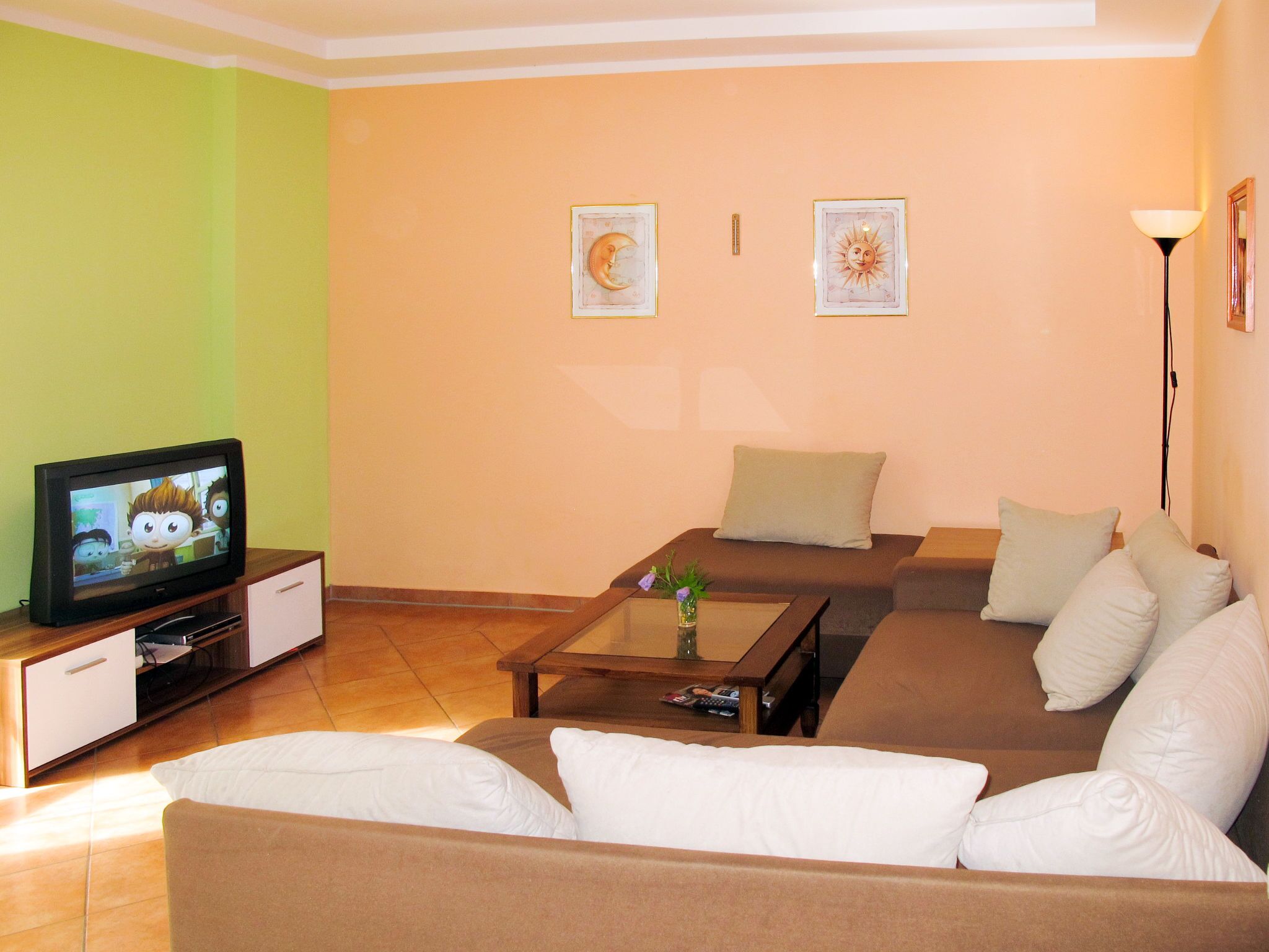 A living room with a brown sofa, a coffee table, and a television on a stand.