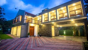 A modern two-story house with a spacious front yard, large windows, and a well-lit entrance. - Villa Senaya (Galle)