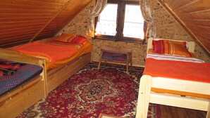 A cozy attic bedroom with two wooden beds, a bench, and a large patterned rug. - Katarina I by Interhome (Plau am See)