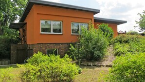 Et moderne hus i to etager med en murstenssokkel og orange vægge.