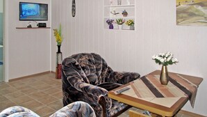 En stue med sofa, sofabord, fjernsyn og dekorative genstande på hylder.