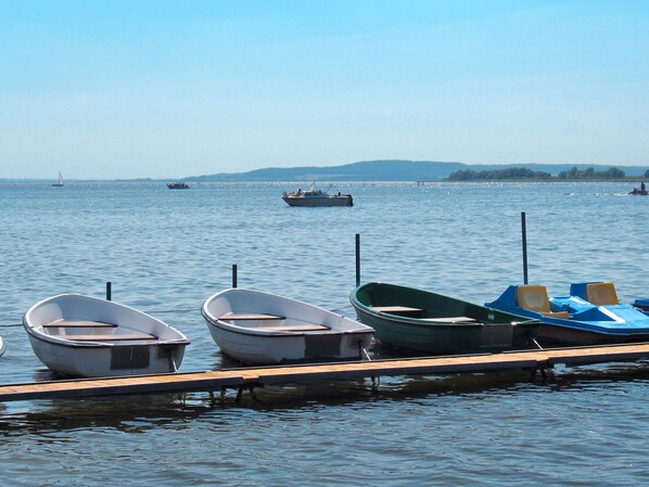 A calm lake with several small boats docked at a wooden pier. - Am See II by Interhome (Verchen)