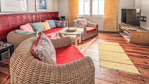 A living room with wicker furniture, a red sofa, a television, and artwork on the wall.