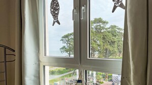 Une pièce dotée d’une grande fenêtre donnant sur un patio aménagé avec des espaces de détente en plein air et de la verdure.