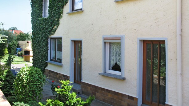 Un bâtiment à l’extérieur beige, doté de nombreuses fenêtres et d’un jardin agrémenté de diverses plantes.