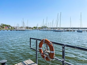 Ein Yachthafen mit mehreren angestaubten Segelbooten, einem Rettungsring an einer Reling und einem hölzernen Steg.
