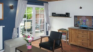 A living room with a sofa, a coffee table, a TV, and a wooden cabinet. - Hühnerhaus by Interhome (Schwarbe)