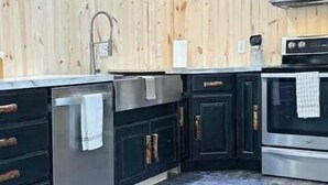 A kitchen with wooden walls, stainless steel appliances, and dark cabinetry. - Wolf Creek (Edgewood)