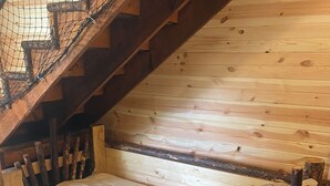 A wooden cabin bedroom with a bed, a wooden staircase, and a wooden floor. - Wolf Creek (Edgewood)