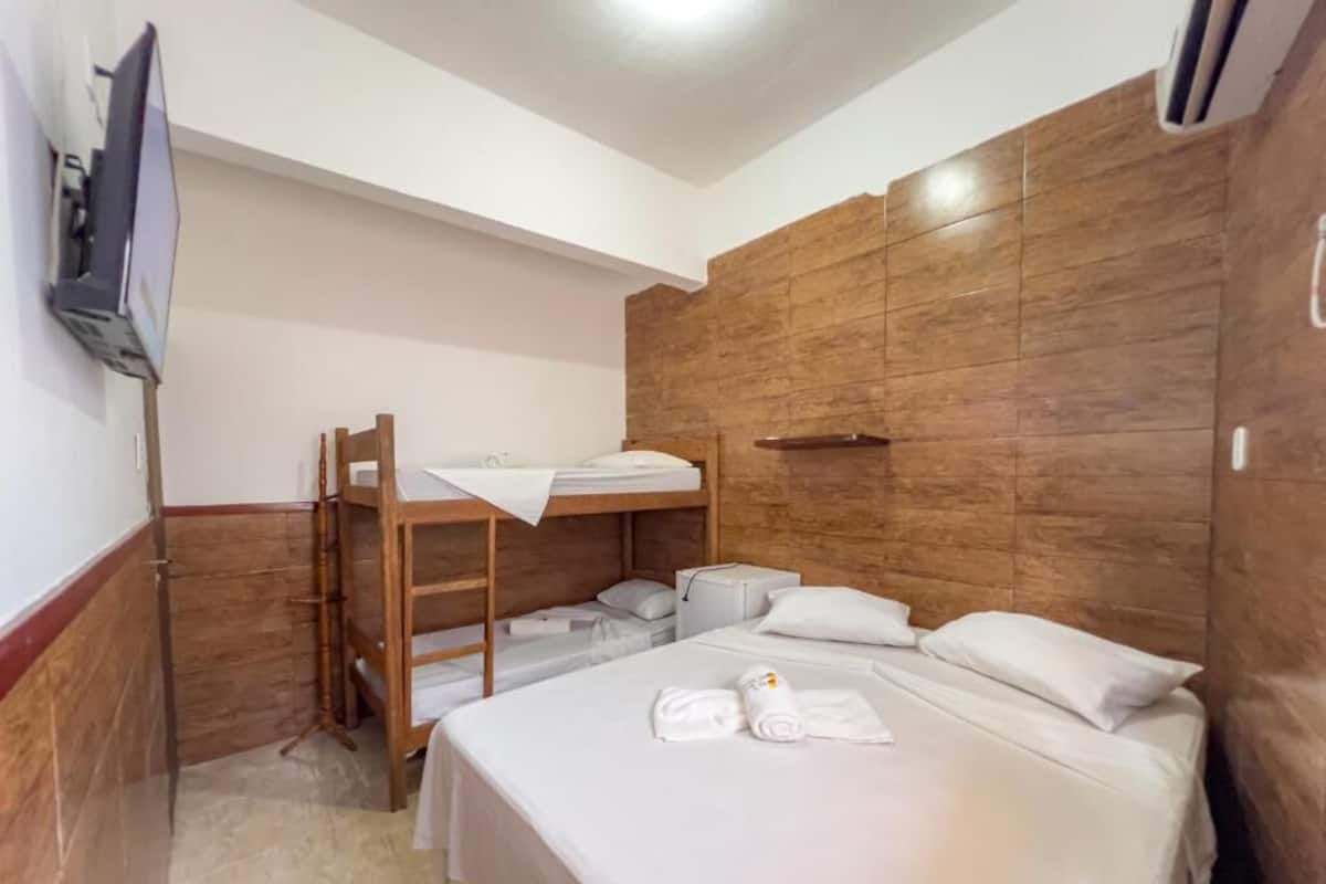 Ein Hotelzimmer mit Etagenbett, Schreibtisch mit Stuhl, Flachbildfernseher und einer Wand mit Holzverkleidung.